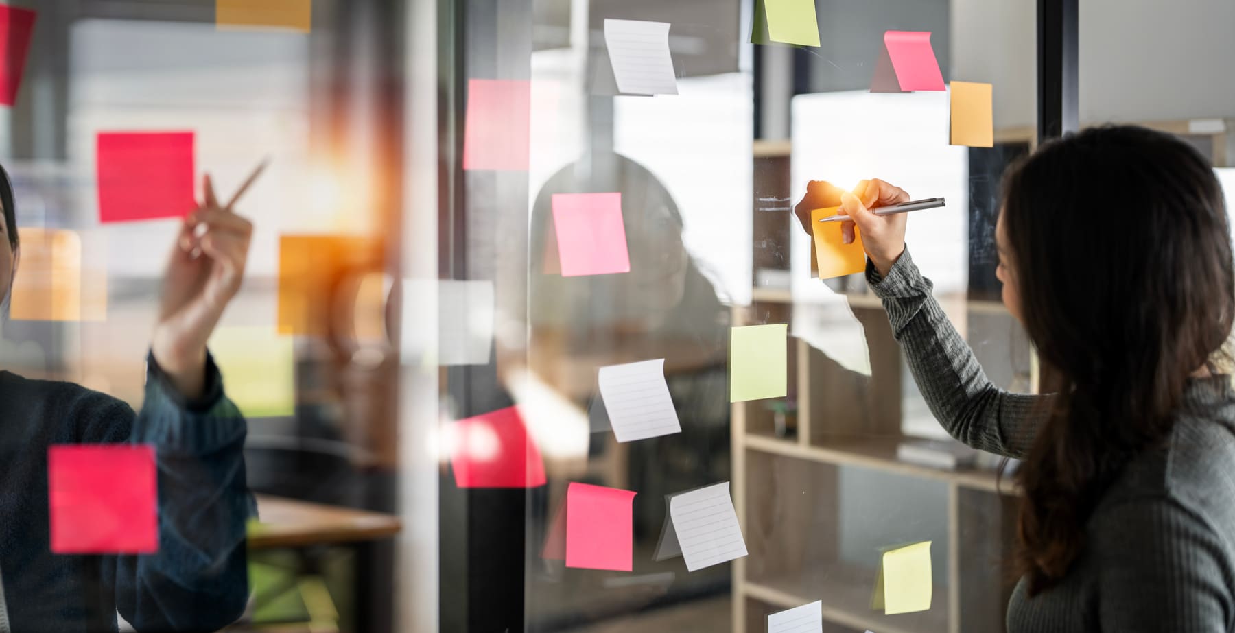 Team mapping a workflow with sticky notes on a glass wall